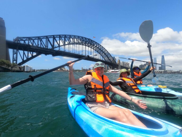 Group of people kayaking in front of Sydney Harbour Bridge