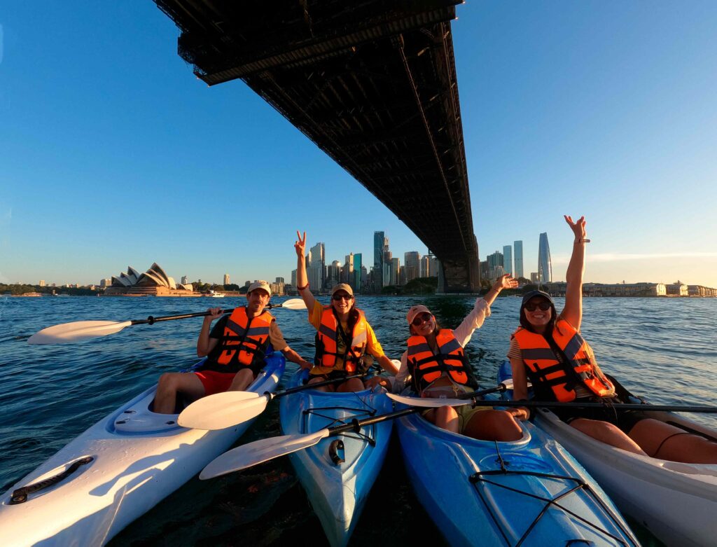 Group of people kayaking below Sydney Harbour Bridge